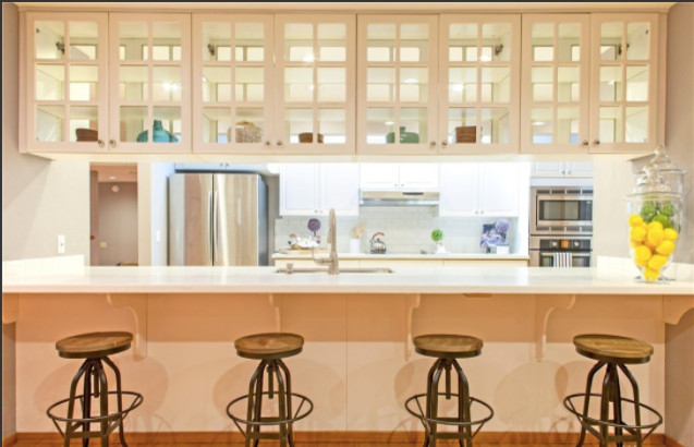 Foto på ett stort funkis kök, med en undermonterad diskho, luckor med glaspanel, vita skåp, bänkskiva i kvarts, rostfria vitvaror, ljust trägolv och en köksö