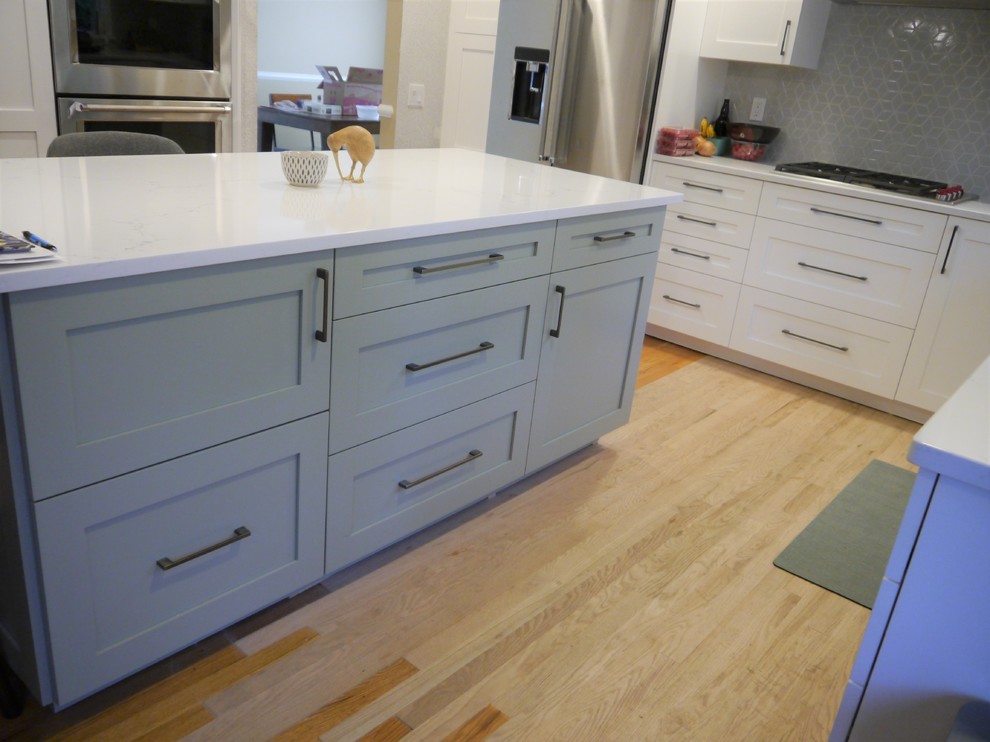 Exempel på ett stort klassiskt vit vitt kök, med en undermonterad diskho, skåp i shakerstil, vita skåp, bänkskiva i kvarts, grått stänkskydd, stänkskydd i keramik, rostfria vitvaror, ljust trägolv, en köksö och gult golv