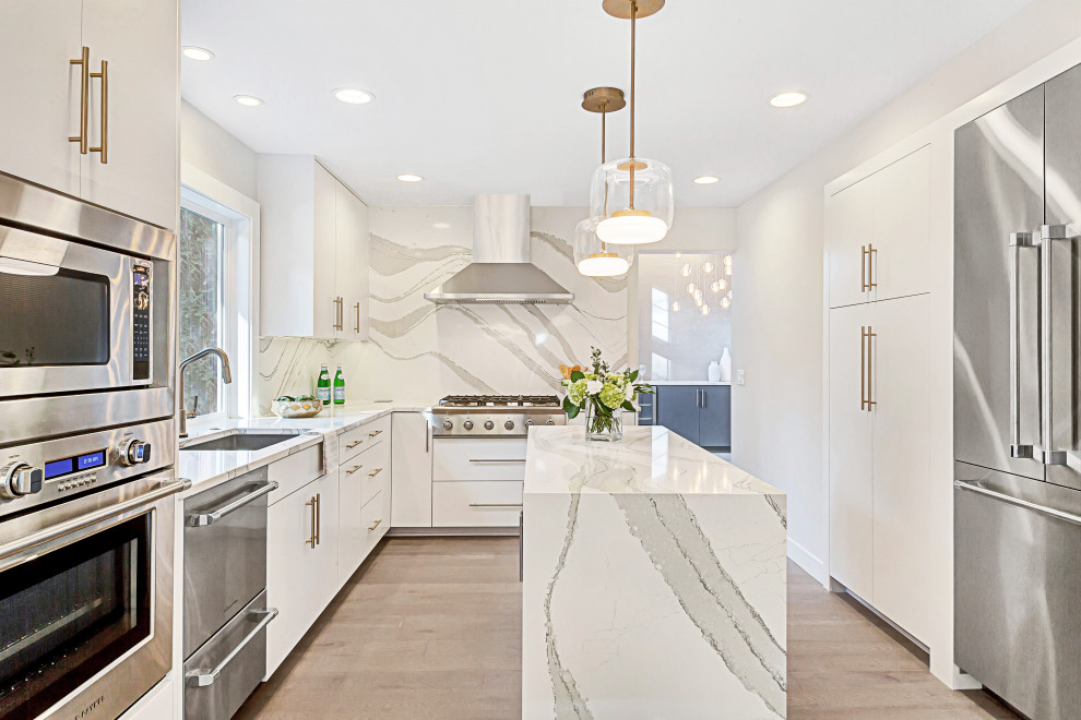 Medium sized modern u-shaped open plan kitchen in Seattle with a single-bowl sink, flat-panel cabinets, white cabinets, engineered stone countertops, white splashback, stone slab splashback, stainless steel appliances, light hardwood flooring, an island, grey floors and white worktops.