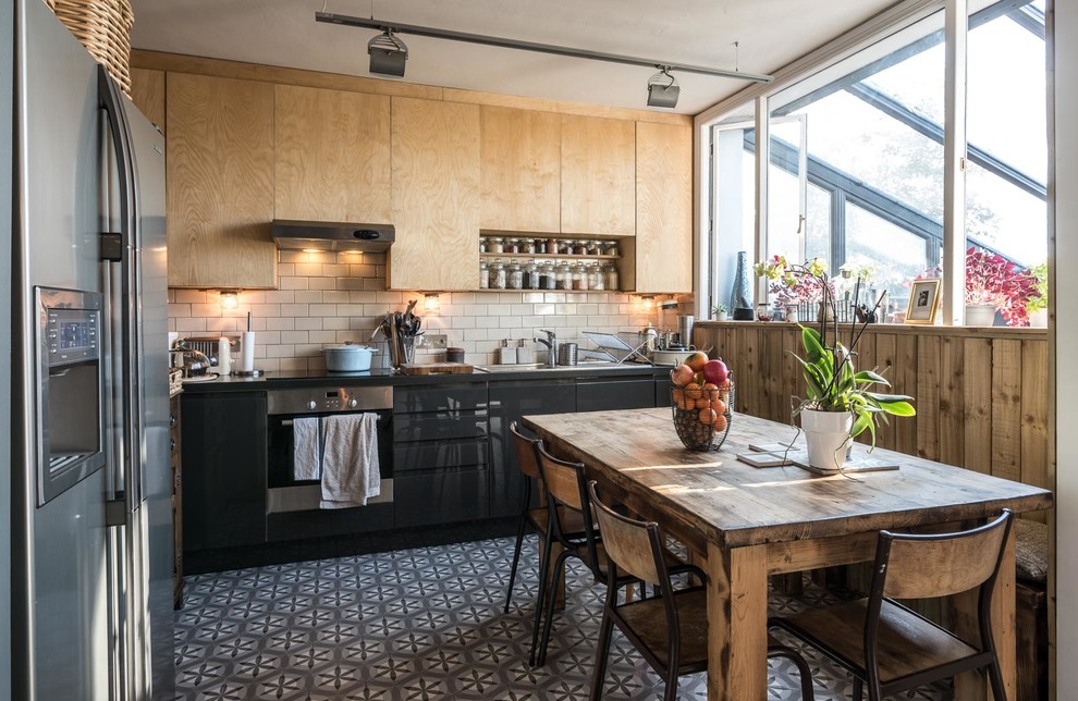 Moderne Wohnküche ohne Insel in L-Form mit flächenbündigen Schrankfronten, Küchenrückwand in Beige, Rückwand aus Metrofliesen und Küchengeräten aus Edelstahl in Sussex