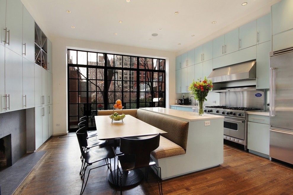Modelo de cocina comedor actual con armarios con paneles lisos, puertas de armario azules y electrodomésticos de acero inoxidable