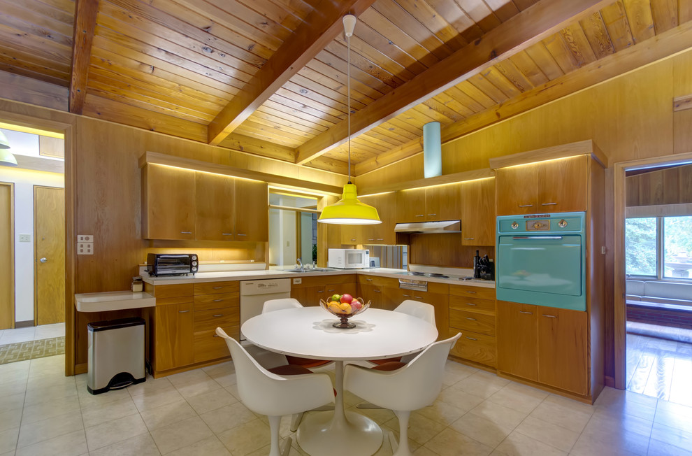 Example of a minimalist l-shaped eat-in kitchen design in Other with colored appliances, flat-panel cabinets and medium tone wood cabinets