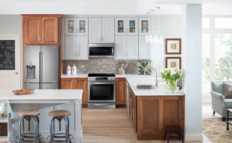 Rustik inredning av ett mellanstort kök, med en dubbel diskho, luckor med profilerade fronter, grå skåp, flerfärgad stänkskydd, stänkskydd i stickkakel, rostfria vitvaror, ljust trägolv och en köksö