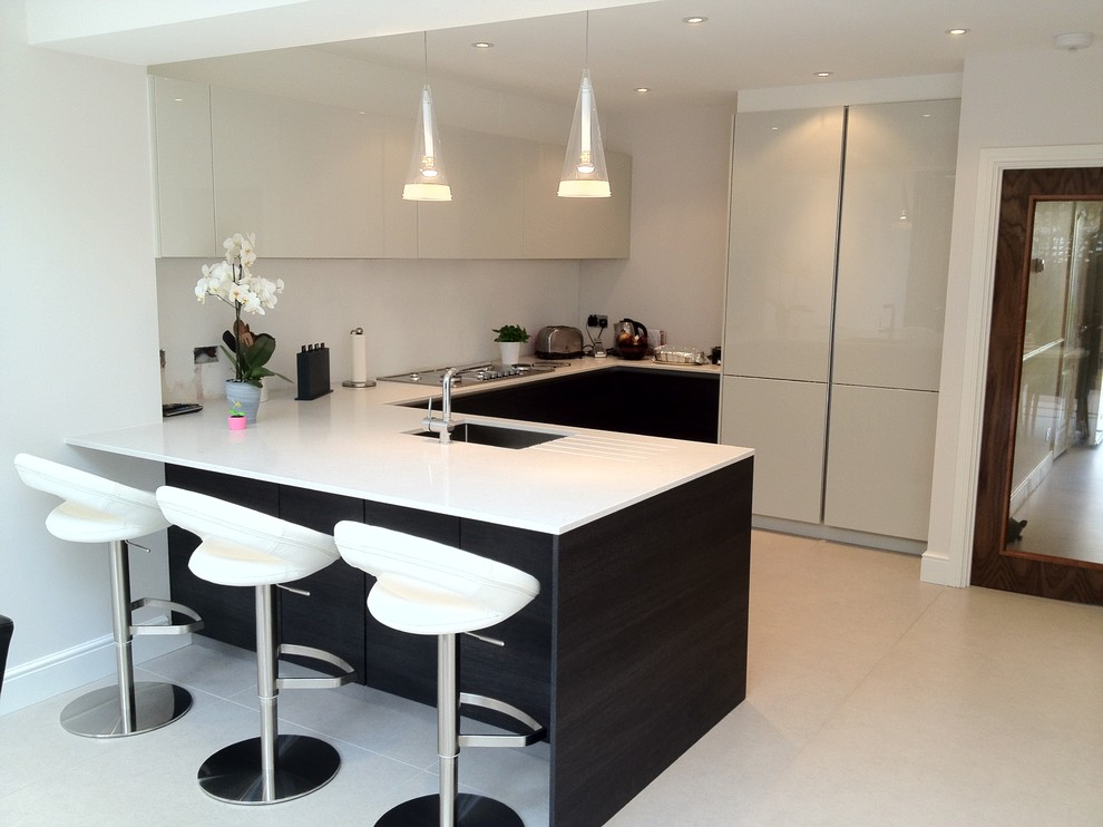 This is an example of a contemporary u-shaped kitchen in London with flat-panel cabinets and integrated appliances.