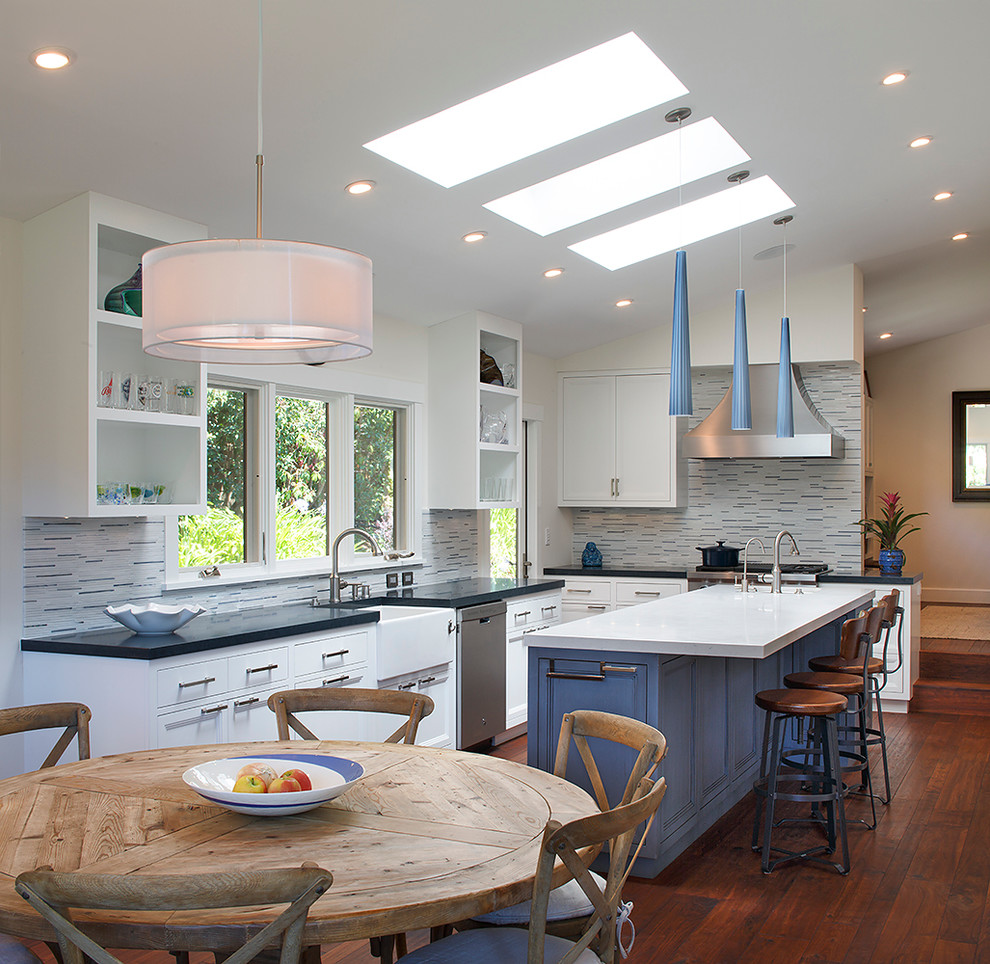 Example of a transitional medium tone wood floor eat-in kitchen design in San Francisco with a farmhouse sink, open cabinets, white cabinets, multicolored backsplash, matchstick tile backsplash, stainless steel appliances and an island