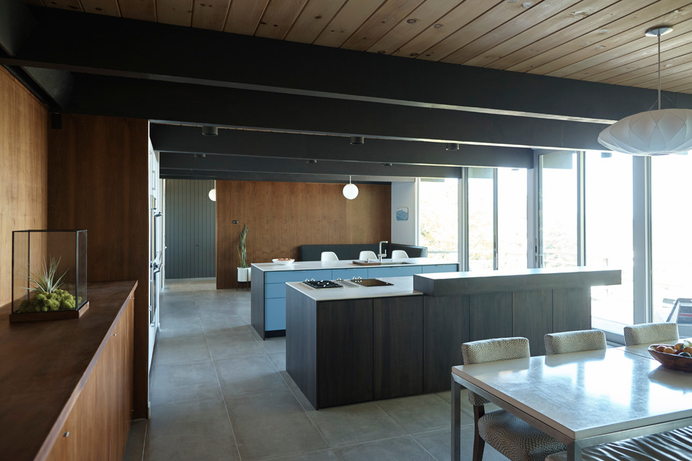 Cette photo montre une cuisine ouverte rétro en bois foncé de taille moyenne avec un placard à porte plane, un plan de travail en surface solide, un sol en carrelage de céramique et 2 îlots.