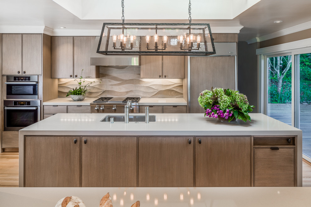 Photo of a large contemporary galley enclosed kitchen in San Francisco with a submerged sink, flat-panel cabinets, light wood cabinets, quartz worktops, beige splashback, porcelain splashback, integrated appliances, light hardwood flooring, an island and beige floors.