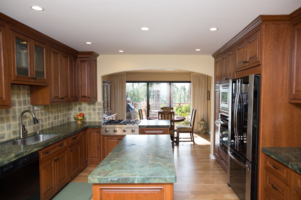 Inspiration for a mid-sized timeless u-shaped light wood floor eat-in kitchen remodel in San Francisco with an undermount sink, raised-panel cabinets, medium tone wood cabinets, granite countertops, green backsplash, ceramic backsplash, stainless steel appliances and an island