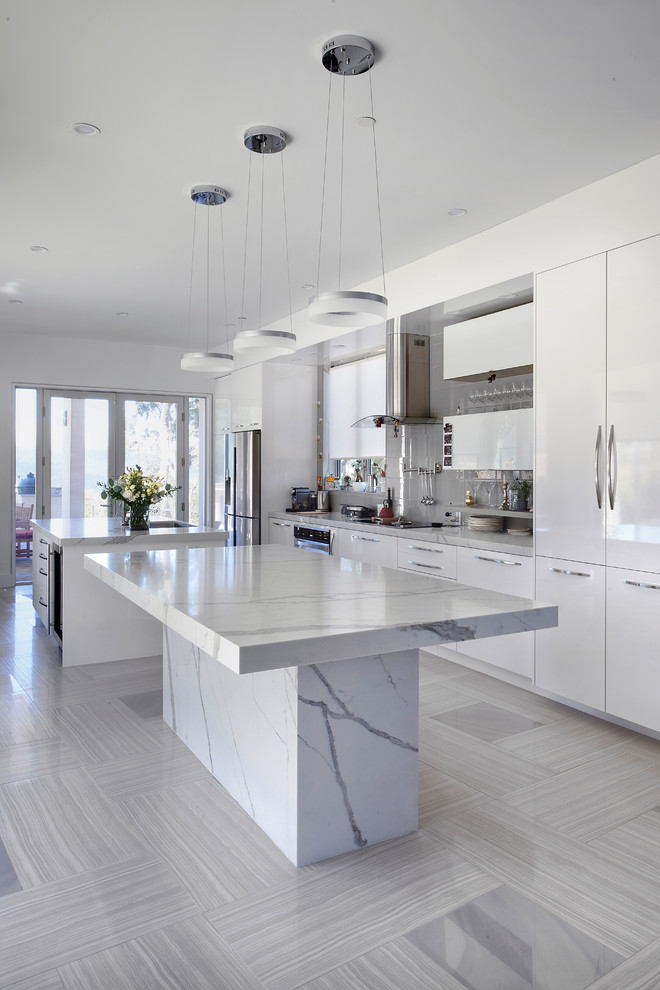 Photo of a large modern galley open plan kitchen in San Francisco with flat-panel cabinets, white cabinets, marble benchtops, multiple islands, an undermount sink, stainless steel appliances, porcelain floors and beige floor.