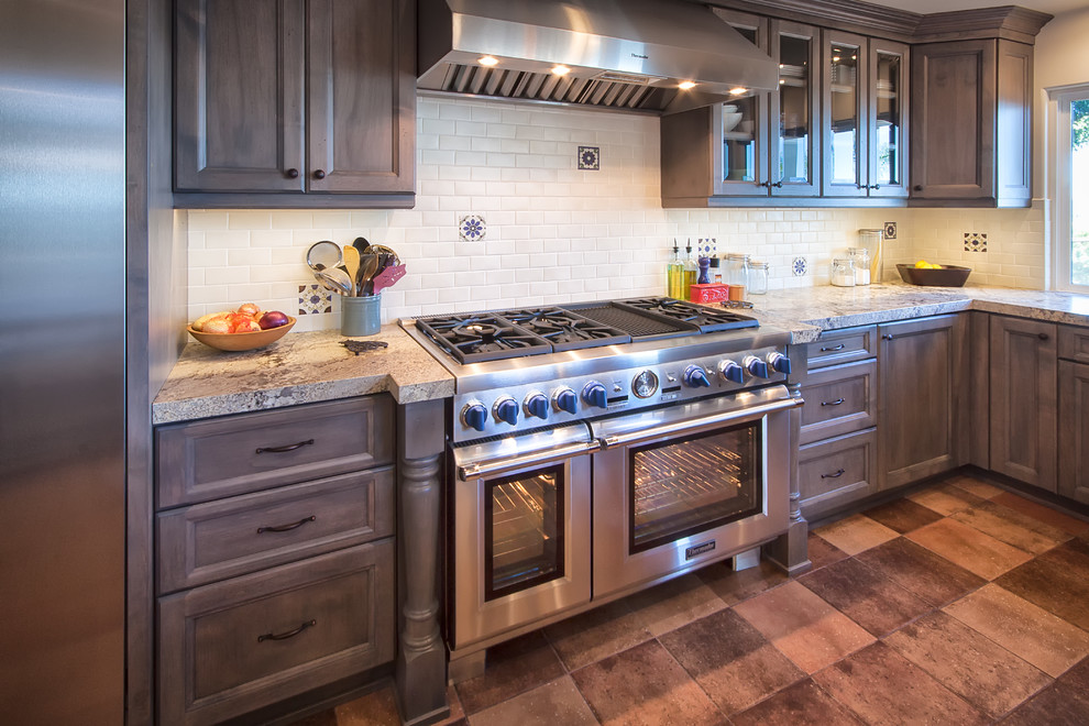 オレンジカウンティにある高級な広いトラディショナルスタイルのおしゃれなキッチン (シェーカースタイル扉のキャビネット、中間色木目調キャビネット、御影石カウンター、白いキッチンパネル、サブウェイタイルのキッチンパネル、シルバーの調理設備、テラコッタタイルの床、アイランドなし、赤い床) の写真