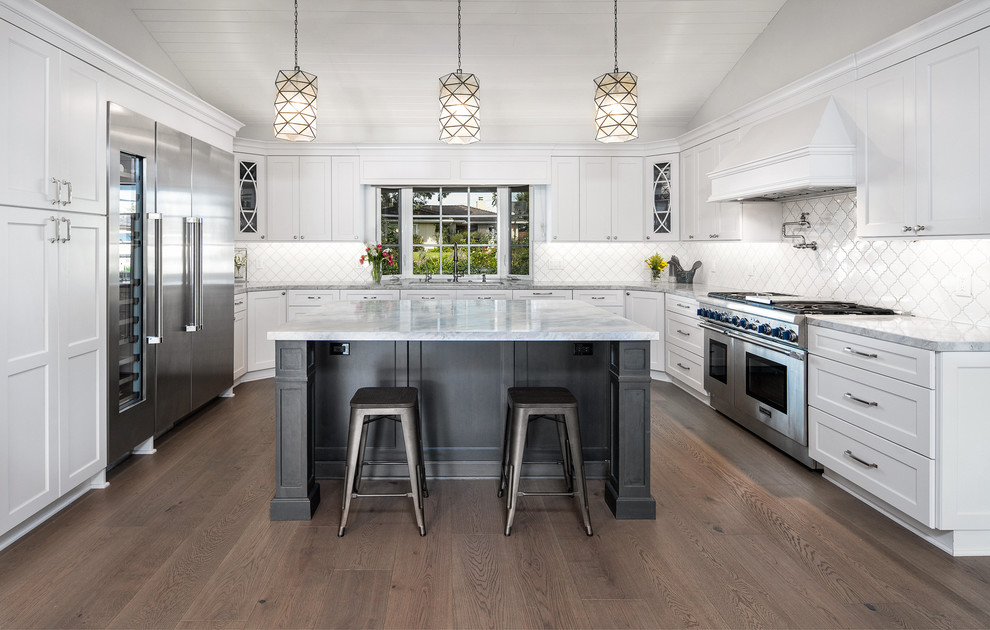 Transitional u-shaped dark wood floor and brown floor kitchen photo in Orange County with shaker cabinets, white cabinets, white backsplash, stainless steel appliances, an island and gray countertops