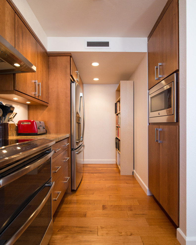 Example of a large trendy l-shaped light wood floor eat-in kitchen design in San Diego with a drop-in sink, flat-panel cabinets, light wood cabinets, granite countertops, beige backsplash, stone slab backsplash, stainless steel appliances and a peninsula