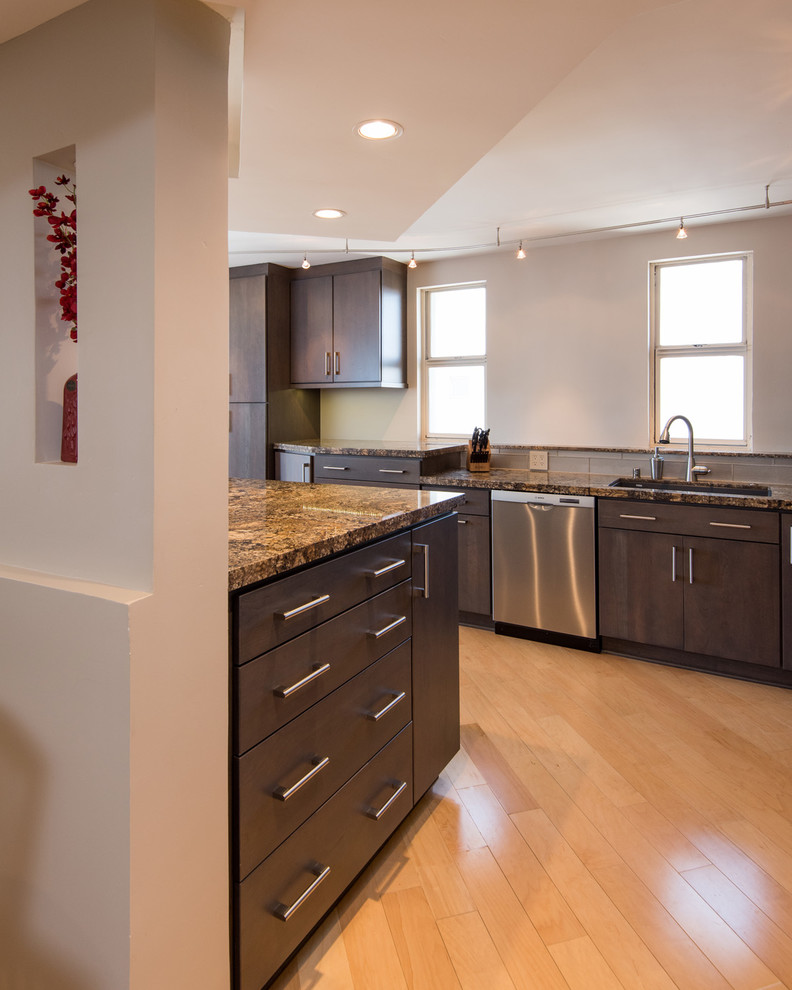 Design ideas for a medium sized contemporary l-shaped kitchen/diner in San Diego with a submerged sink, flat-panel cabinets, dark wood cabinets, granite worktops, grey splashback, glass tiled splashback, stainless steel appliances, light hardwood flooring and an island.