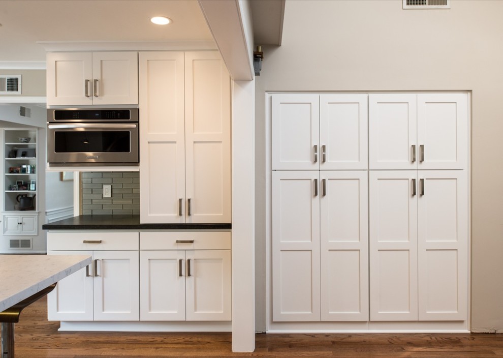 Exempel på ett avskilt, mycket stort modernt u-kök, med en nedsänkt diskho, luckor med infälld panel, vita skåp, granitbänkskiva, grått stänkskydd, stänkskydd i glaskakel, rostfria vitvaror, mellanmörkt trägolv och en köksö