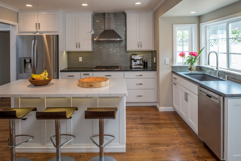 Huge minimalist u-shaped medium tone wood floor enclosed kitchen photo in San Diego with a drop-in sink, recessed-panel cabinets, white cabinets, granite countertops, gray backsplash, glass tile backsplash, stainless steel appliances and an island