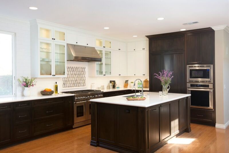 Example of a large minimalist l-shaped medium tone wood floor open concept kitchen design in San Diego with a single-bowl sink, raised-panel cabinets, dark wood cabinets, quartzite countertops, white backsplash, ceramic backsplash, paneled appliances and an island