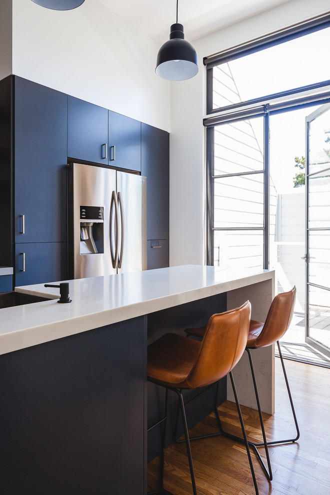 Aménagement d'une cuisine moderne avec un placard à porte plane et des portes de placard bleues.