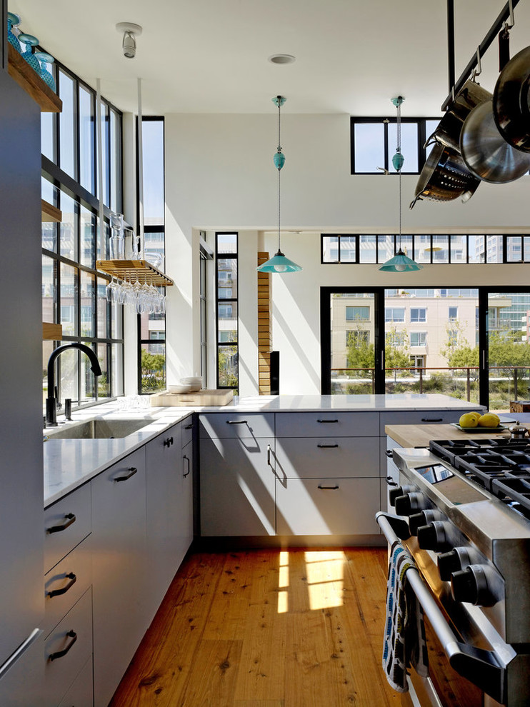 Exemple d'une cuisine encastrable et parallèle moderne avec un placard à porte plane, plan de travail en marbre et des portes de placard bleues.