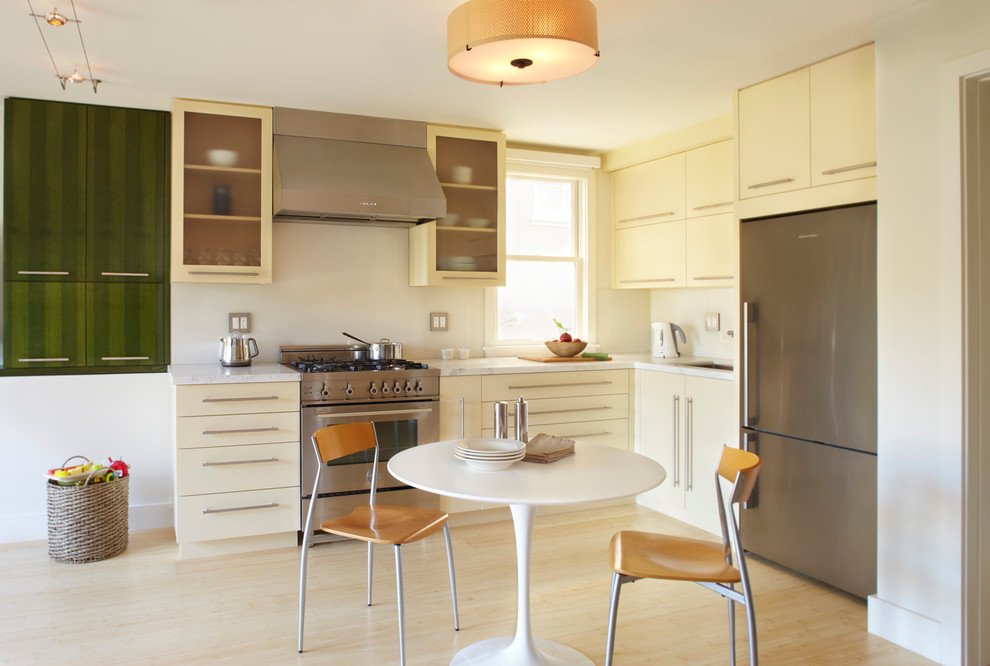 Ejemplo de cocina moderna con armarios con paneles lisos, puertas de armario beige y electrodomésticos de acero inoxidable