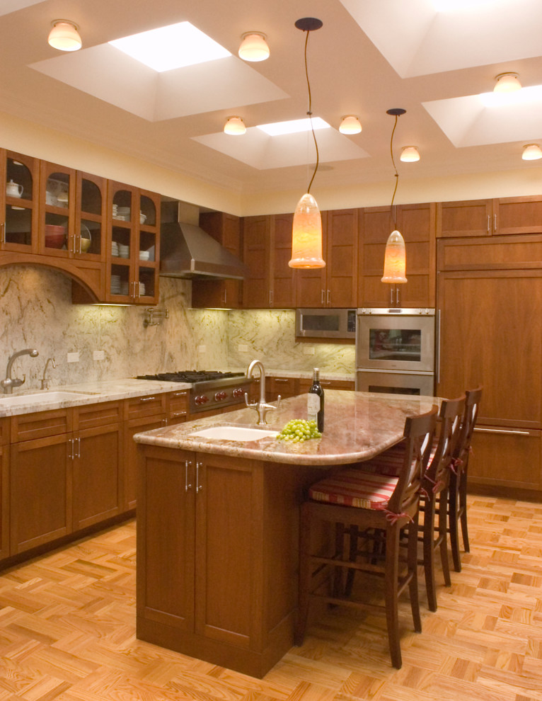 Foto på ett stort vintage l-kök, med granitbänkskiva, integrerade vitvaror, en undermonterad diskho, skåp i shakerstil, skåp i mellenmörkt trä, flerfärgad stänkskydd, stänkskydd i sten, ljust trägolv, en köksö och brunt golv