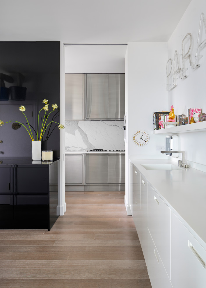 This is an example of a medium sized modern kitchen in San Francisco with brown floors, a submerged sink, flat-panel cabinets, quartz worktops, white splashback, stone slab splashback, light hardwood flooring and white worktops.