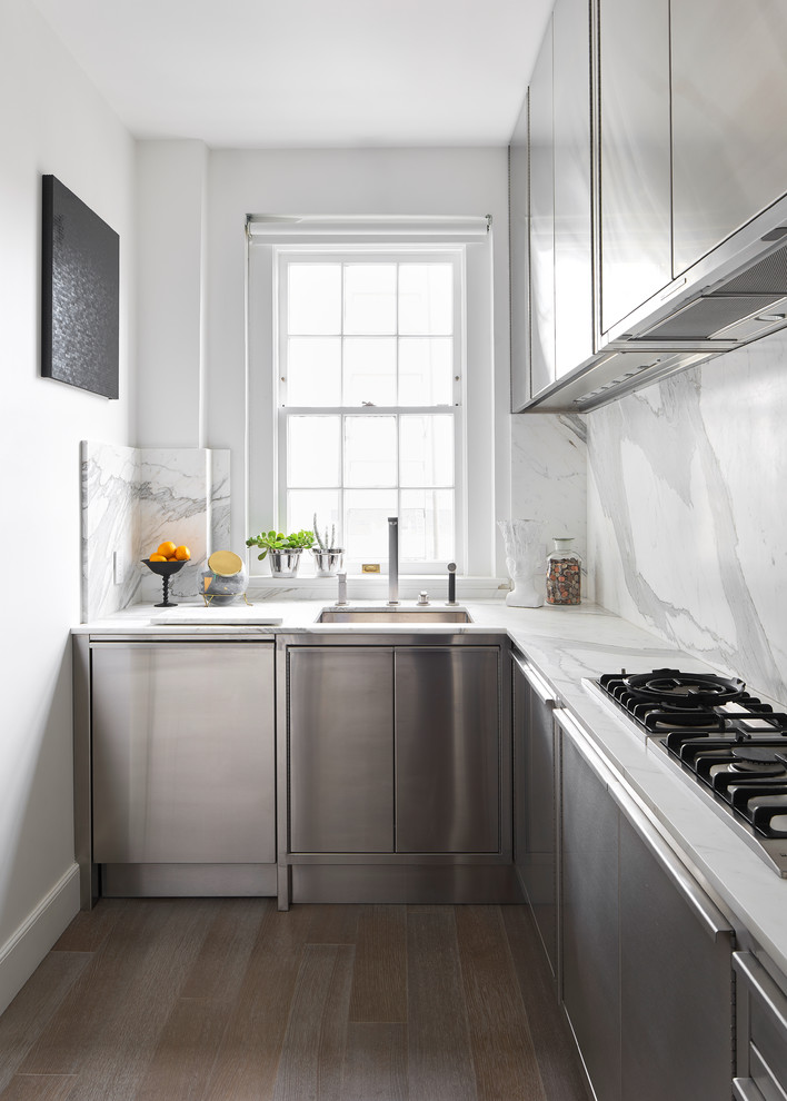 Inredning av ett modernt litet vit vitt l-kök, med en undermonterad diskho, släta luckor, skåp i rostfritt stål, vitt stänkskydd, stänkskydd i sten, mörkt trägolv och brunt golv
