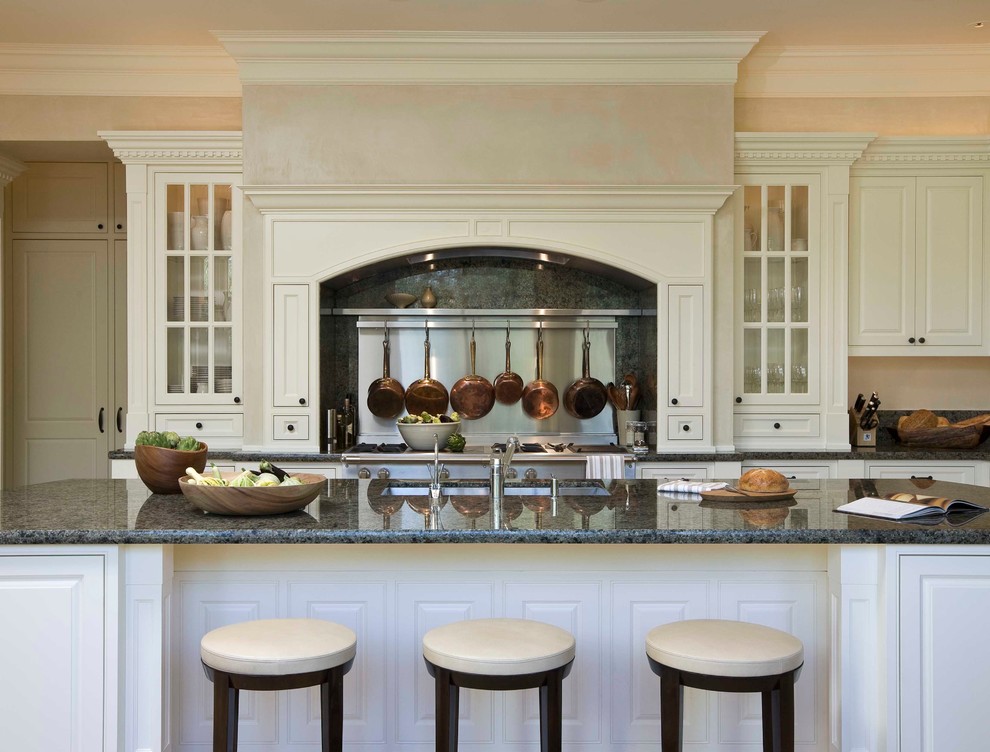 Inspiration för stora klassiska kök, med luckor med profilerade fronter, vita skåp, en undermonterad diskho, granitbänkskiva, grönt stänkskydd, stänkskydd i sten, rostfria vitvaror, kalkstensgolv och en köksö