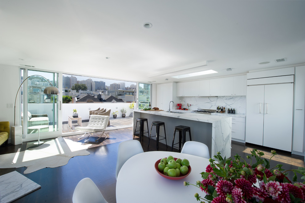 На фото: параллельная кухня-гостиная в современном стиле с плоскими фасадами, белыми фасадами, белым фартуком и техникой под мебельный фасад с