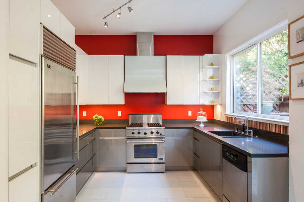 На фото: п-образная, отдельная кухня в современном стиле с врезной мойкой, плоскими фасадами, серыми фасадами, столешницей из кварцевого агломерата, разноцветным фартуком и техникой из нержавеющей стали с