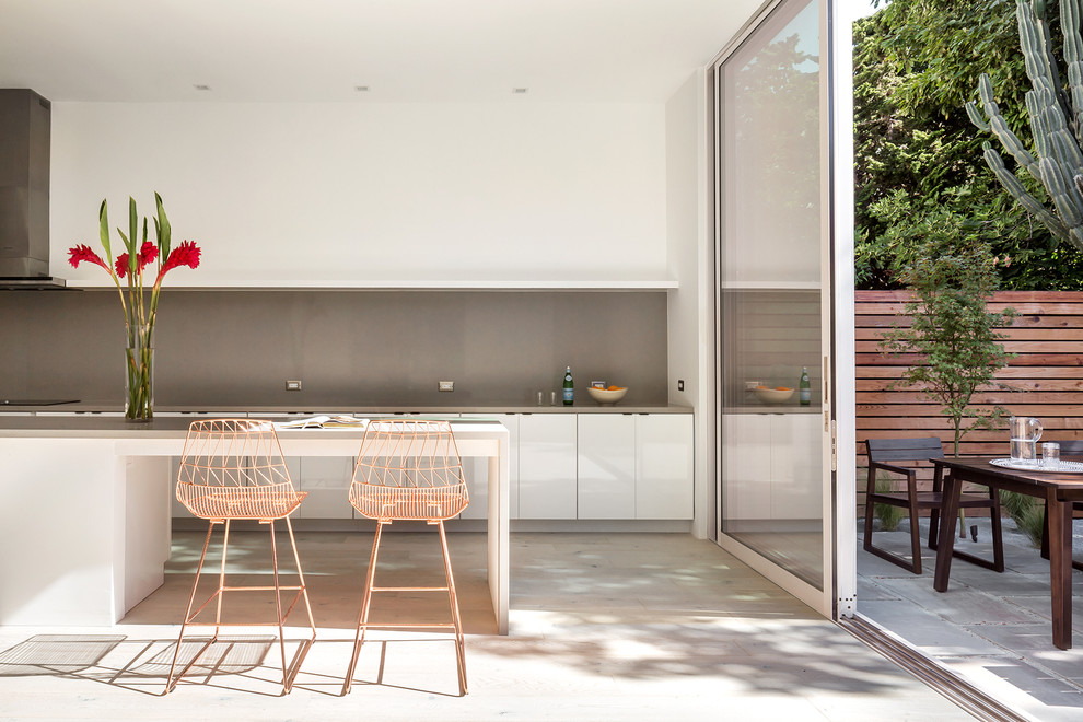 Esempio di una cucina design di medie dimensioni con ante lisce, parquet chiaro, ante bianche, paraspruzzi grigio, pavimento beige, top grigio e top in cemento