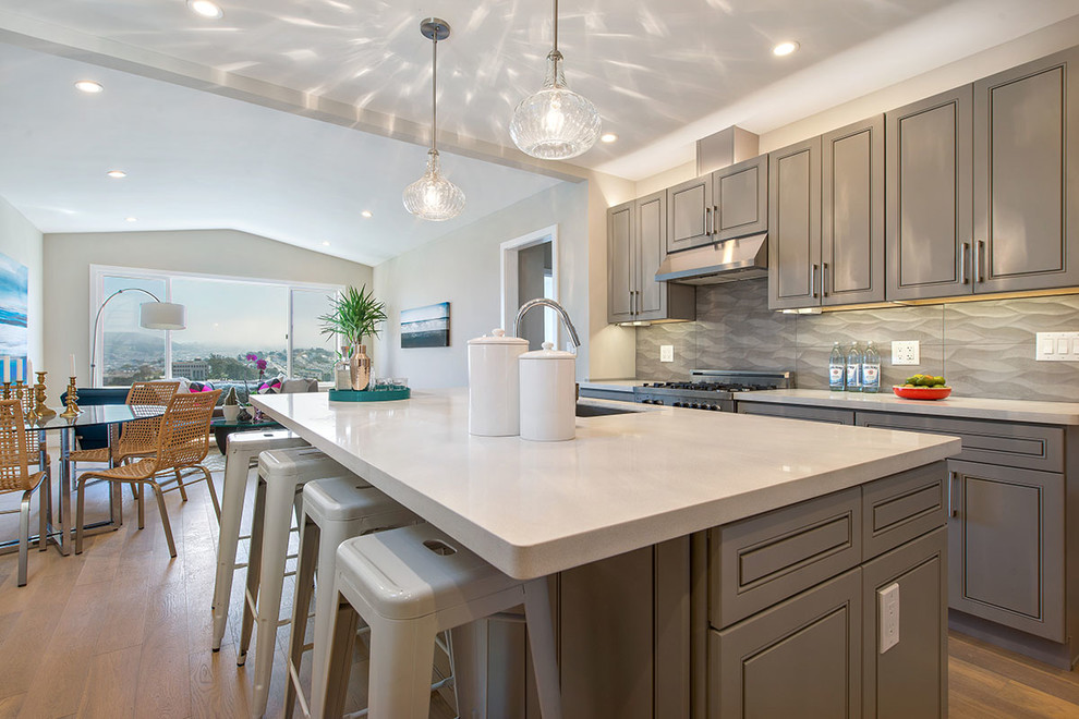 Inspiration for a small transitional galley light wood floor open concept kitchen remodel in San Francisco with a single-bowl sink, shaker cabinets, gray cabinets, quartz countertops, gray backsplash, porcelain backsplash, stainless steel appliances and an island
