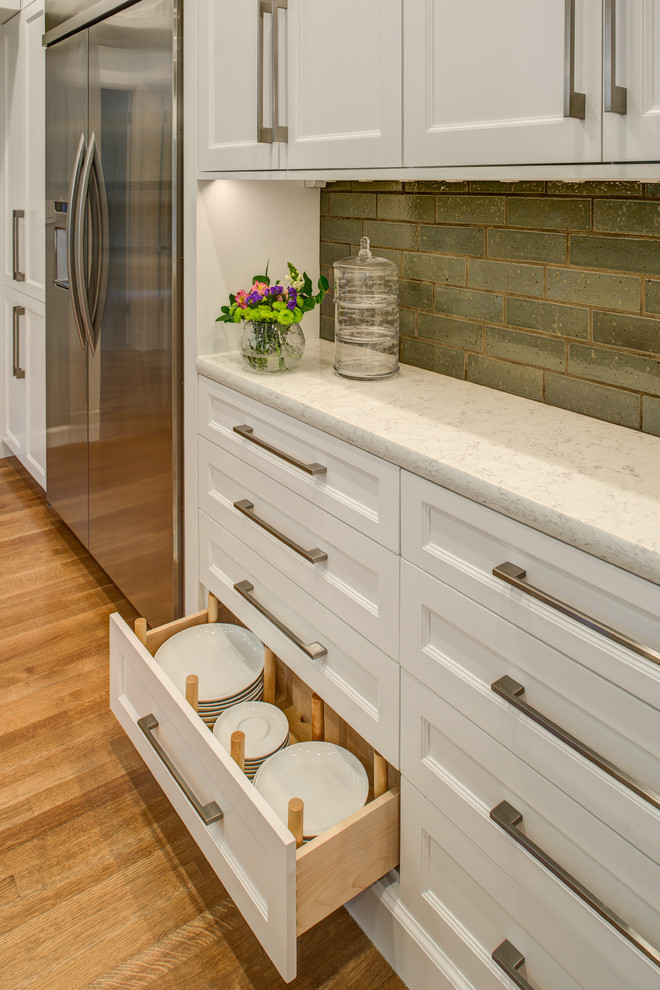 This is an example of a medium sized traditional u-shaped open plan kitchen in San Francisco with a belfast sink, recessed-panel cabinets, white cabinets, engineered stone countertops, grey splashback, metro tiled splashback, stainless steel appliances, medium hardwood flooring and a breakfast bar.