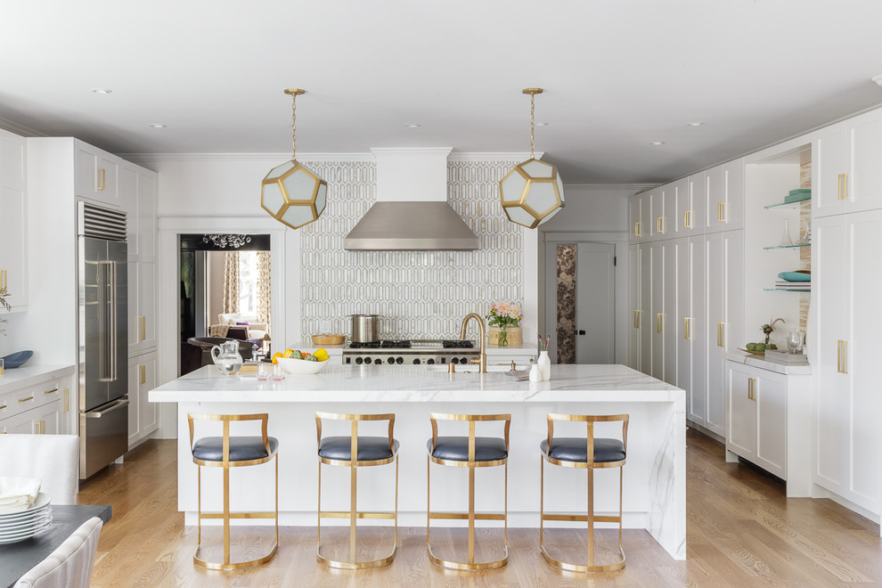 Example of a large transitional u-shaped light wood floor and brown floor open concept kitchen design in San Francisco with white cabinets, multicolored backsplash, glass tile backsplash, stainless steel appliances, an island, an undermount sink, shaker cabinets and marble countertops
