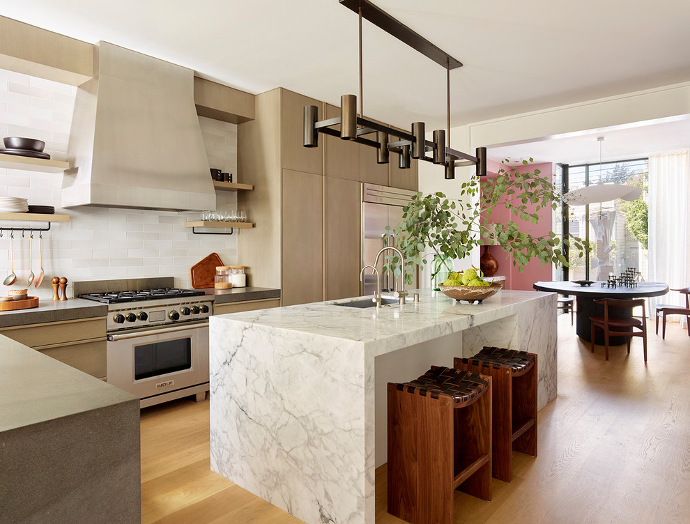 Moderne Küche in L-Form mit Unterbauwaschbecken, flächenbündigen Schrankfronten, hellen Holzschränken, Küchenrückwand in Weiß, Küchengeräten aus Edelstahl, braunem Holzboden, Kücheninsel, braunem Boden und weißer Arbeitsplatte in San Francisco
