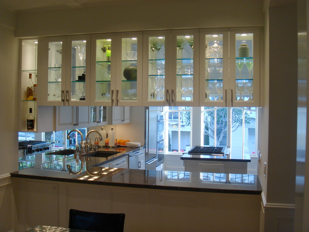 Immagine di una cucina abitabile design con ante di vetro, top in granito, paraspruzzi bianco e elettrodomestici in acciaio inossidabile