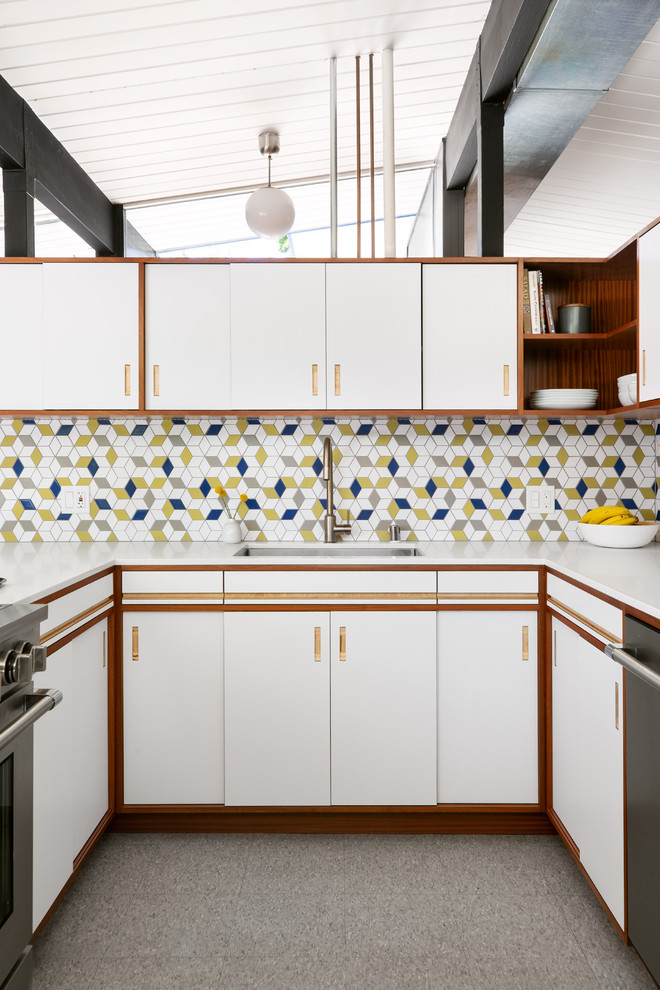 Inspiration for a retro u-shaped kitchen in San Francisco with a submerged sink, flat-panel cabinets, white cabinets, multi-coloured splashback, mosaic tiled splashback, stainless steel appliances, grey floors and white worktops.
