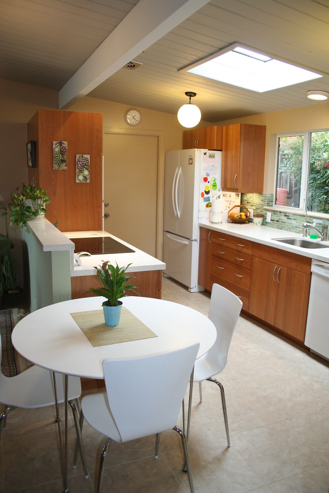 Exempel på ett litet 60 tals kök, med vita vitvaror, en undermonterad diskho, släta luckor, skåp i mellenmörkt trä, bänkskiva i kvarts, flerfärgad stänkskydd, stänkskydd i glaskakel och klinkergolv i porslin