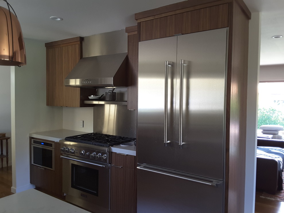 Immagine di una cucina design di medie dimensioni con ante lisce, ante in legno scuro, elettrodomestici in acciaio inossidabile e penisola