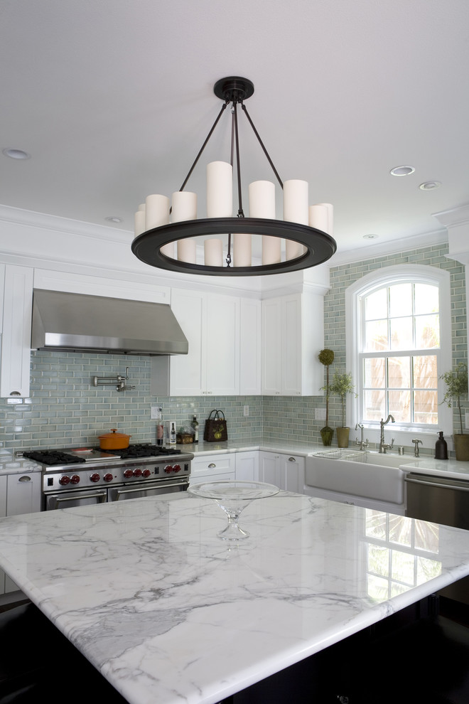 Example of a classic l-shaped dark wood floor open concept kitchen design in San Francisco with a farmhouse sink, shaker cabinets, white cabinets, marble countertops, blue backsplash, ceramic backsplash, stainless steel appliances and an island