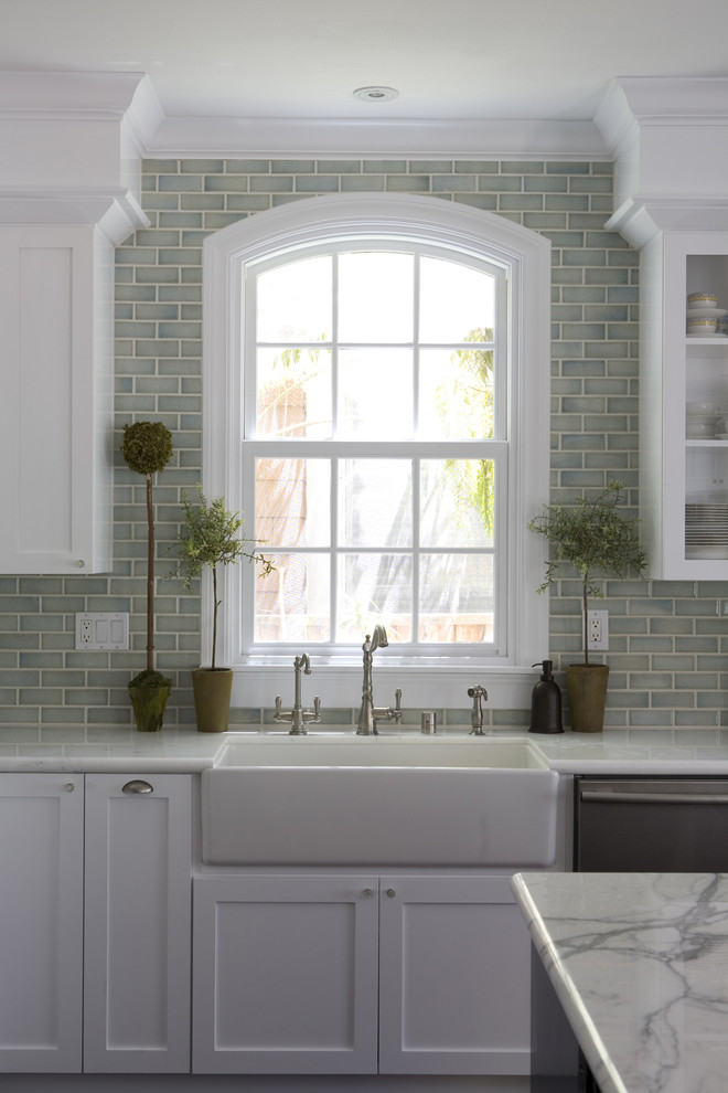 Elegant l-shaped dark wood floor kitchen photo in San Francisco with a farmhouse sink, shaker cabinets, white cabinets, marble countertops, blue backsplash, ceramic backsplash, stainless steel appliances and an island