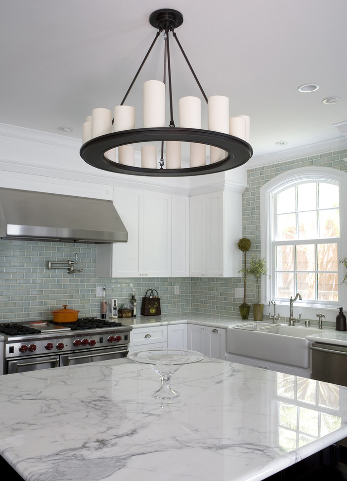 Example of a classic l-shaped dark wood floor open concept kitchen design in San Francisco with a farmhouse sink, shaker cabinets, white cabinets, marble countertops, blue backsplash, ceramic backsplash, stainless steel appliances and an island