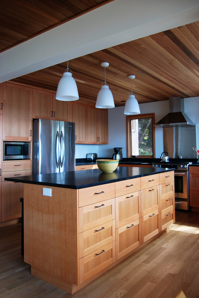 This is an example of a medium sized contemporary u-shaped open plan kitchen in Seattle with recessed-panel cabinets, medium wood cabinets and an island.