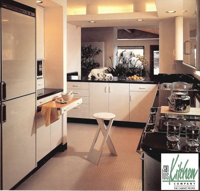 Пример оригинального дизайна: параллельная кухня в стиле модернизм с обеденным столом, врезной мойкой, плоскими фасадами, белыми фасадами, гранитной столешницей, черным фартуком, фартуком из каменной плиты и белой техникой