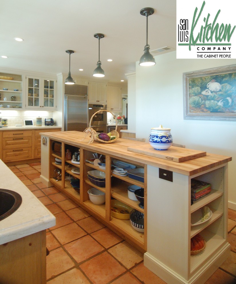 На фото: отдельная, угловая кухня в классическом стиле с фасадами с выступающей филенкой, светлыми деревянными фасадами и деревянной столешницей
