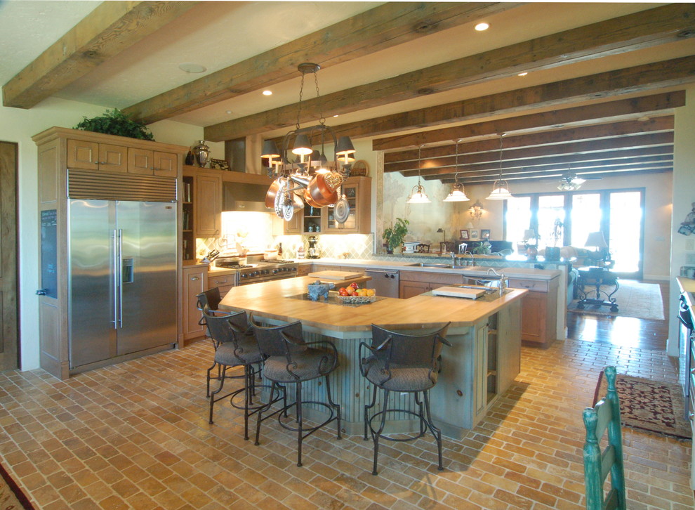 Inspiration for a large mediterranean u-shaped brick floor open concept kitchen remodel in San Luis Obispo with an undermount sink, recessed-panel cabinets, medium tone wood cabinets, wood countertops, green backsplash, ceramic backsplash, stainless steel appliances and an island