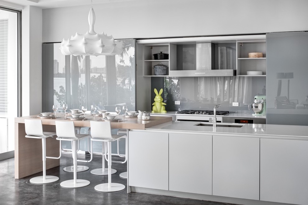 Photo of a medium sized contemporary grey and white galley kitchen/diner in Miami with a submerged sink, open cabinets, grey splashback, glass sheet splashback, concrete flooring, an island, engineered stone countertops, stainless steel appliances, grey cabinets and grey floors.