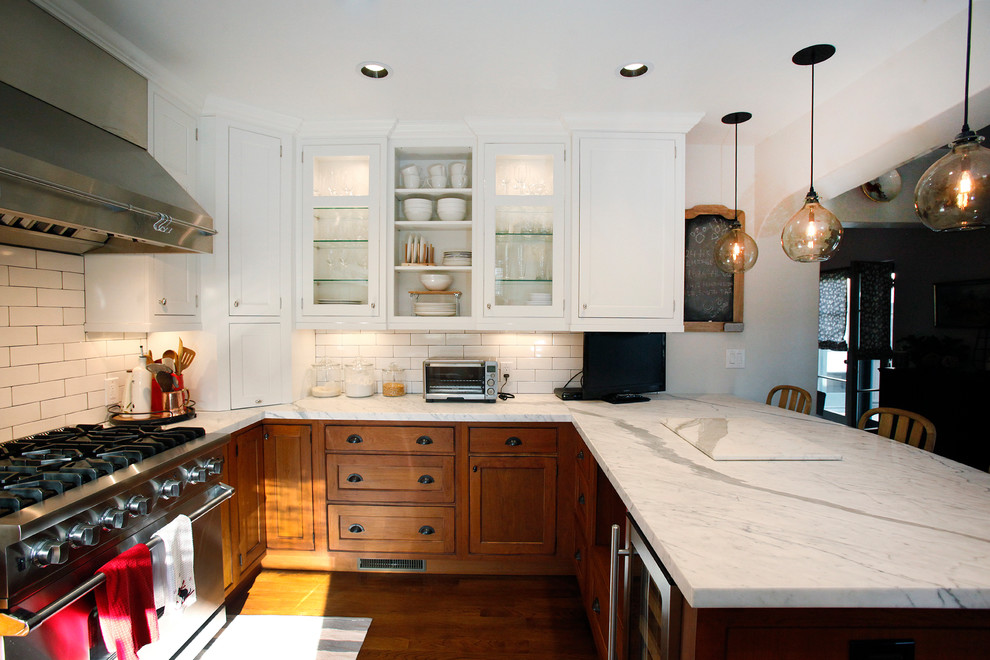 Klassisk inredning av ett mellanstort vit vitt kök, med en rustik diskho, luckor med profilerade fronter, skåp i mellenmörkt trä, marmorbänkskiva, vitt stänkskydd, stänkskydd i keramik, rostfria vitvaror, mellanmörkt trägolv, en halv köksö och brunt golv