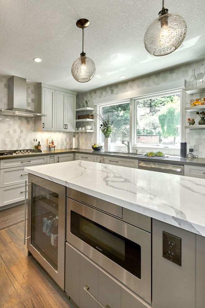 This is an example of a medium sized classic u-shaped kitchen in San Francisco with a submerged sink, recessed-panel cabinets, grey cabinets, engineered stone countertops, white splashback, marble splashback, stainless steel appliances, medium hardwood flooring, an island, brown floors and grey worktops.
