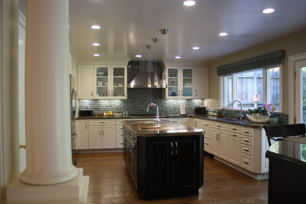 Inredning av ett modernt mellanstort brun brunt kök, med en enkel diskho, luckor med glaspanel, vita skåp, granitbänkskiva, rostfria vitvaror, grönt stänkskydd, stänkskydd i keramik, mellanmörkt trägolv och brunt golv