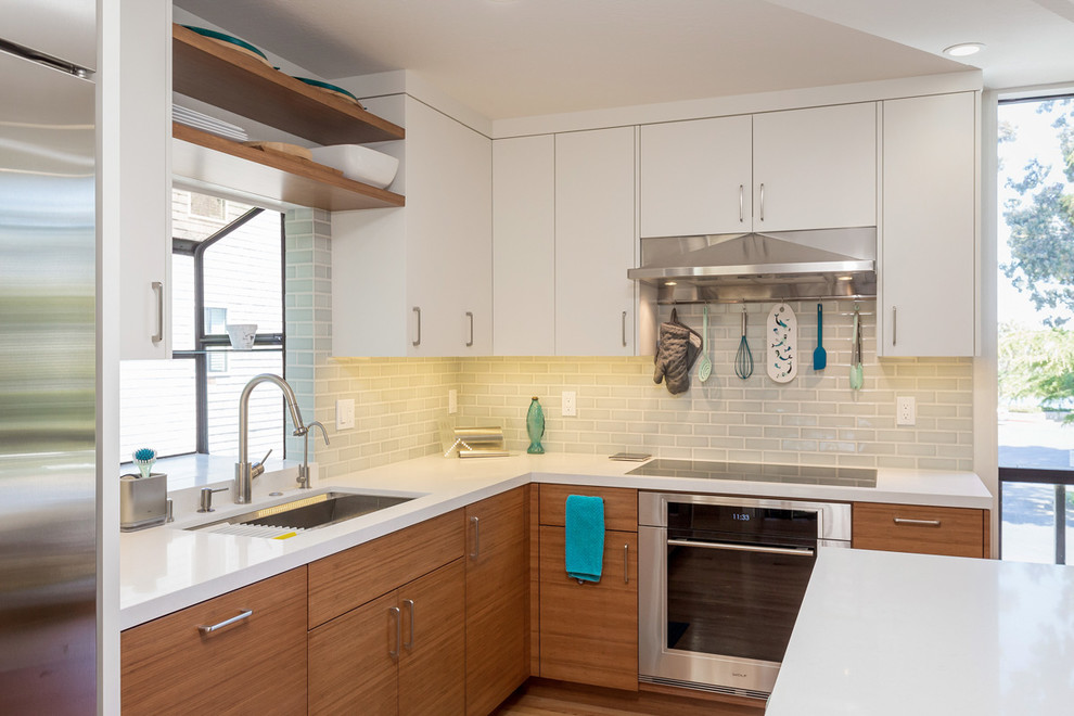 Kitchen - mid-sized contemporary l-shaped medium tone wood floor and brown floor kitchen idea in San Francisco with an undermount sink, flat-panel cabinets, white cabinets, solid surface countertops, gray backsplash, subway tile backsplash, stainless steel appliances, an island and white countertops